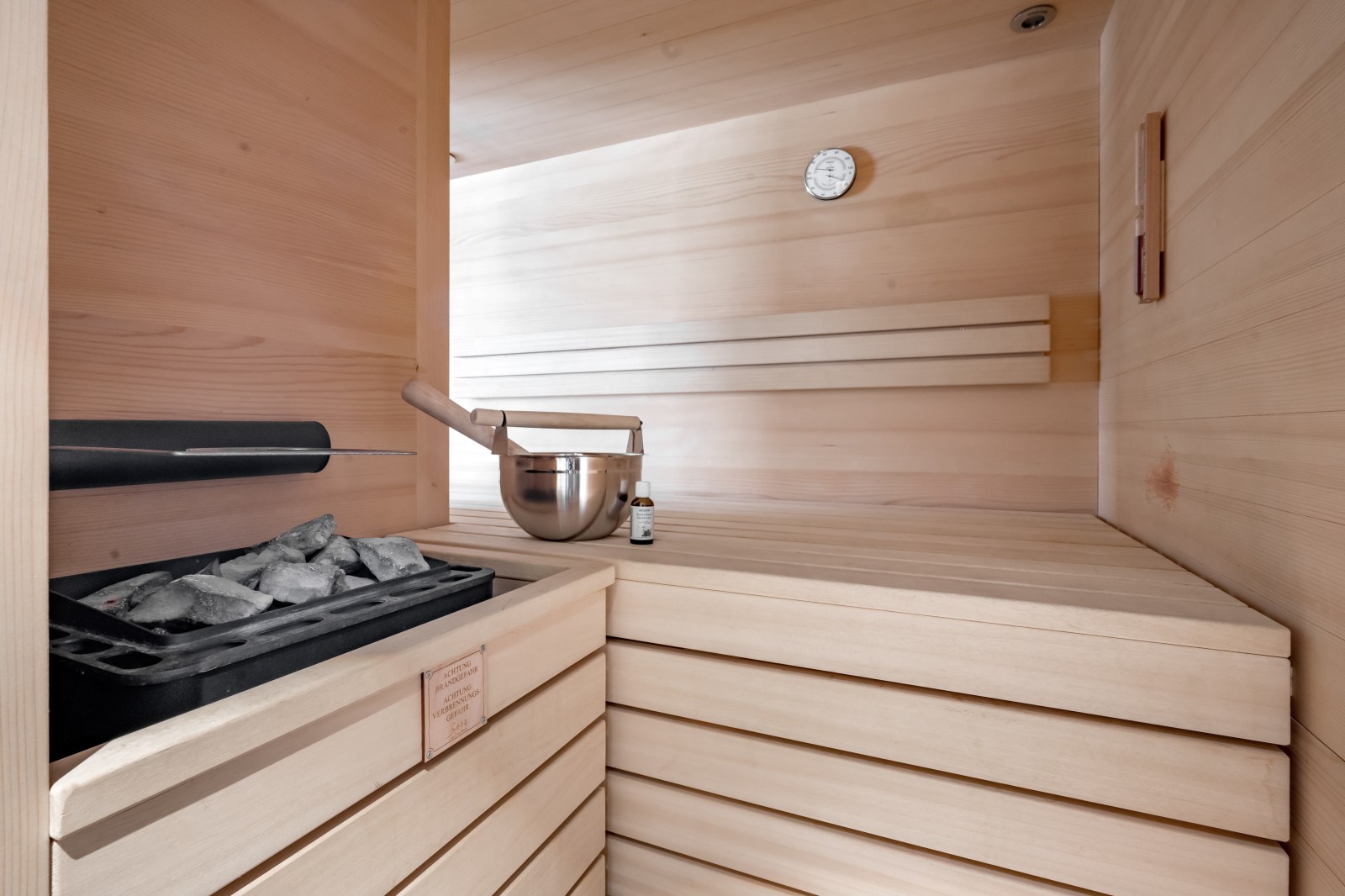 Bright wooden sauna with stone heater, ladle, and essential oils in the Private SPA Suite Exclusive at Chalet Mondschein, Stuben am Arlberg